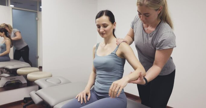 Physical therapist giving sportive young woman a neck massage to relief tension