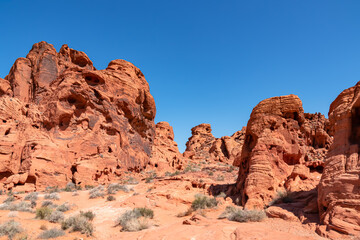 Exterior view of windstone arch and fire cave in Valley of Fire State Park, Mojave desert, Nevada, USA. Scenic view of beehive shaped red sandstone rock formations. Barren deserted landscape in summer