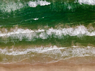 Sandy Oceans Waves Crashing on a Beach From Above