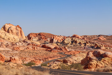 Panoramic view of endless winding empty road in Valley of Fire State Park leading to red Aztec Sandstone Rock formations and desert vegetation in Mojave desert, Overton, Nevada, USA. Freedom road trip