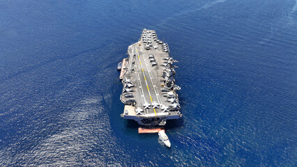 Aerial drone photo of latest technology nuclear powered aircraft carrier anchored in deep blue open...