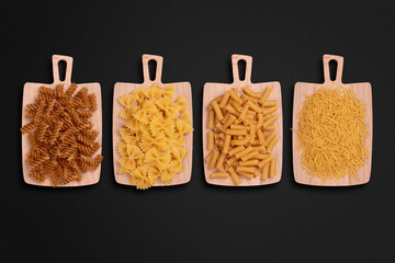 Variety of dry pasta types and shapes on cutting boards, top view with copy space for text.