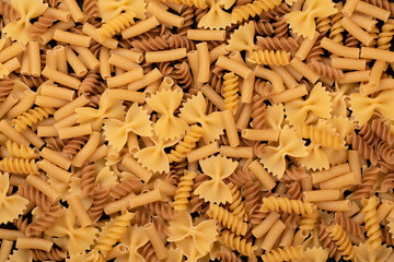 Variety of types and shapes of dry pasta background, top view.