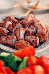 A plate full of fried meat, kebabs on the background of vegetables