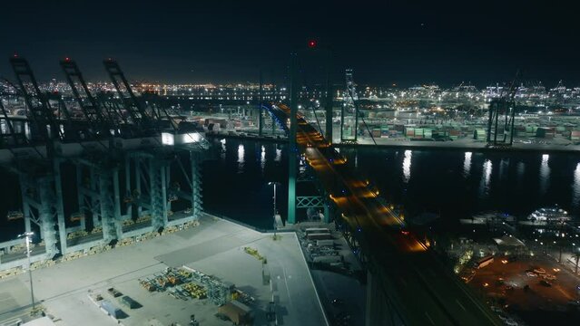 Drone shot of cars driving on suspension bridge at night in The Port of Los Angeles, San Pedro Bay, West coast, California, USA. International commercial shipping port with containers, 4k footage