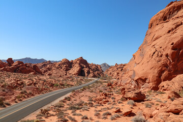 Panoramic view of endless winding empty Mouse tank road in Valley of Fire State Park through canyons of red Aztec Sandstone Rock formations and desert vegetation in Mojave desert, Overton, Nevada, USA