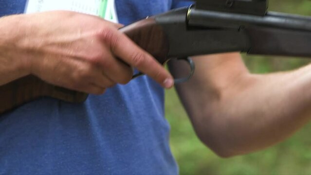 following hand held close up shot of a man loading the gun with the shooting cartridge