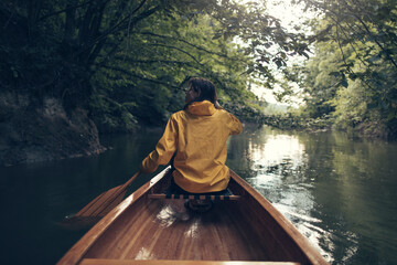 Rear view of woman paddling canoe on rainforest lake