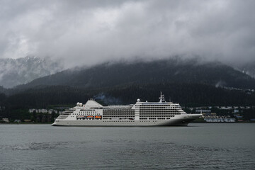 Luxury Silver cruiseship cruise ship liner Muse arrival into port of Juneau, Alaska during nature adventure Last Frontier cruising with dramatic panoramic landscape vacation