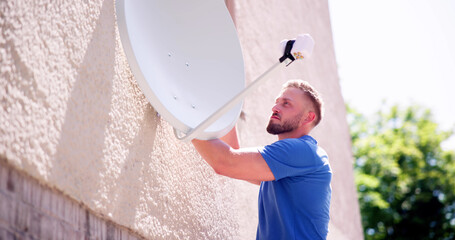 Technician Installing TV Satellite Dish On Wall