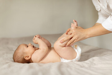 Constipation in babies. Mother doing gymnastics with her newborn child to relieve gases, moving...