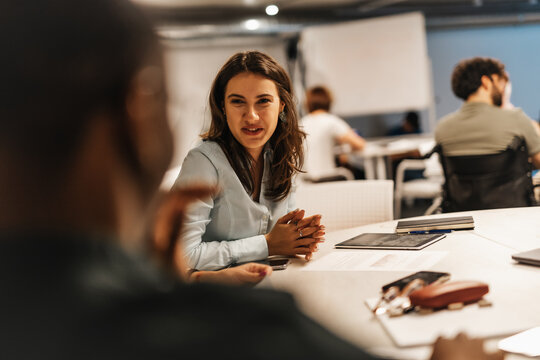 Beautiful female having fun conversation while learning new stuff at work with her teammates.