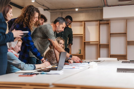 Inter-generational, multicultural group of businesspeople starting up a new project at the company. Team leader giving instructions to colleagues