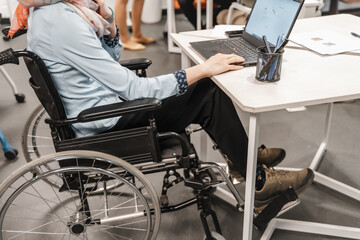 Close up photo of disabled female employee in wheelchair working on lap top