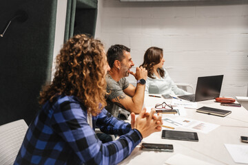 Different-aged businesspeople having fun and smiling during brainstorming in a meeting room at the office