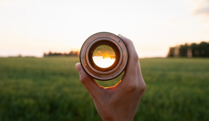 Looking to the green wheat field in the lights of evening sun. Point of view. Selective focus.
