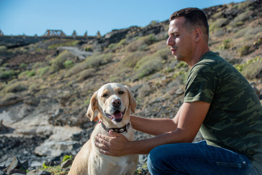 Caucasian dog trainer cuddles labrador dog after successful work session.