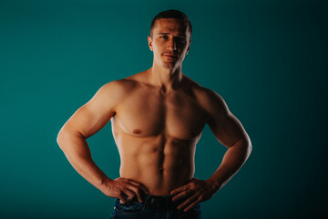 Happy, fit, male sports person posing on turquoise background in studio with slight smile on his face
