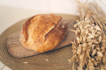 Fresh homemade wheat bread is ready for breakfast in the morning light. It lies on a wooden board with space for copying. High quality photo
