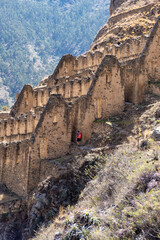 A man on his back with a red backpack entering an Inca ruin.