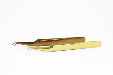 Pair of gold and copper metal shiny tweezers beauty tools for eyelash extension beauty salon procedure. Professional accessories and products for lash application on white background

