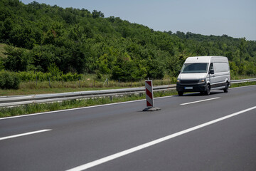 White modern delivery small shipment cargo courier van moving fast on motorway road to city urban...