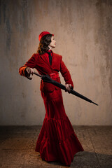 Mary Poppins. A stylish lady in a red old-fashioned suit with a hat and a lace umbrella