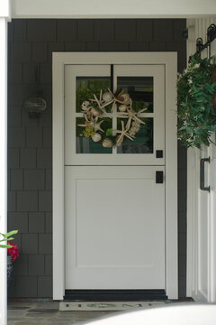 vintage beach cottage with taupe wood shingles and seashell wreath on the front door