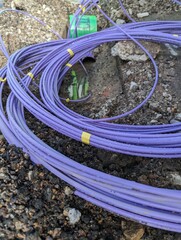 Fibre optic cable coming out of a trench curled up waiting to be installed for the UK gigabit...