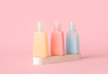Plaster podium with bottles of different cosmetic products on pink background