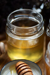 fresh natual  linden honey in glass jar with wooden  honey spoon around herb flowers. close up