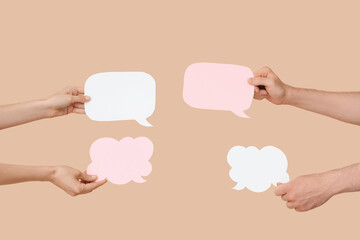 Different hands with speech bubbles on beige background