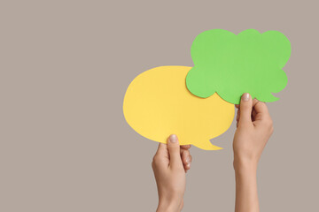 Female hands with speech bubbles on grey background