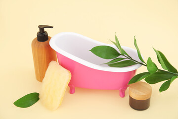 Composition with small bathtub, bath supplies and plant branch on color background