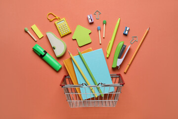 Shopping basket with different school stationery on orange background