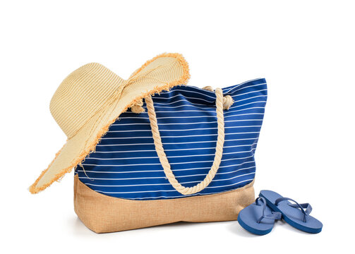 Stylish beach bag with straw hat and flip-flops on white background