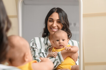 Young woman with her baby near mirror in bedroom