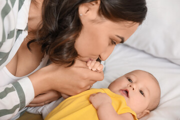 Young woman kissing her baby in bedroom, closeup