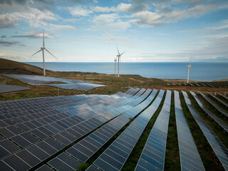 Aerial shot of two sources of renewable energy: solar panels and windmills.
