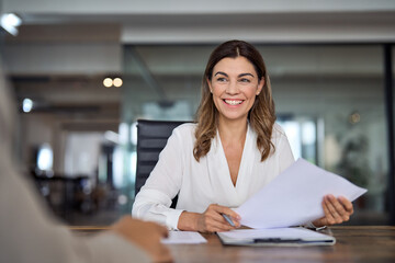 Smiling mature business woman hr holding cv document at job interview. Happy mid aged professional...