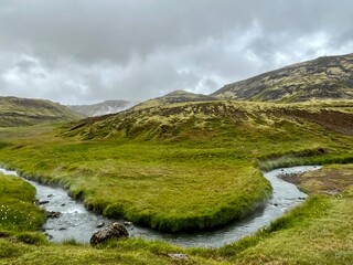 View while hiking to Reykjadalur Hot Springsor the Steam Valley is located in the South part of Iceland. Views of smokey hills winding rivers and mud pools visible.