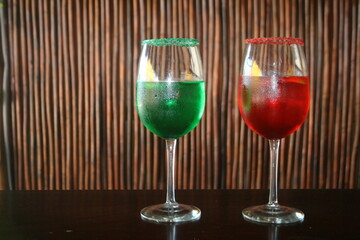 Ricos cócteles en un vaso con frutos rojos y verdes con rodaja de limón sobre un fondo de madera,...