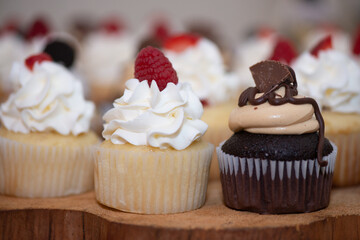 Chocolate cup cakes with whip cream and chocolate candy toppings on dessert table wedding reception