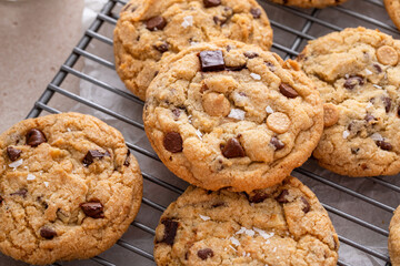 Chocolate chip cookies on a cooling rack with flaky salt served with milk