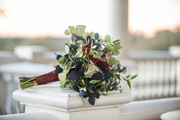 Majestic red,pink and white bouquet with blue and green leaves outdoors on fancy stair railing