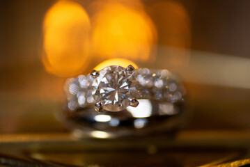Gorgeous sparkling diamond engagement ring in warm setting with warm bokeh and soft focus background
