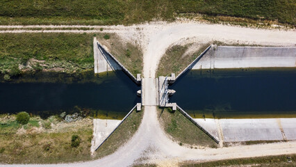 Dam on the river, drone shot. Concrete dam and river channel in the field.