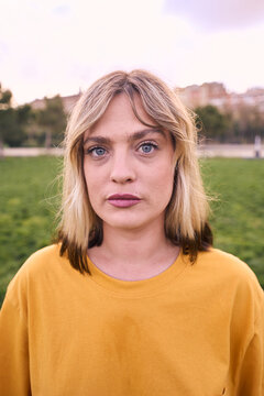 Vertical Portrait of a woman looking at camera outdoors with serious expression. Beautiful girl is cute. She looks unsmiling and attractive and confident. This caucasian female is posing sadness