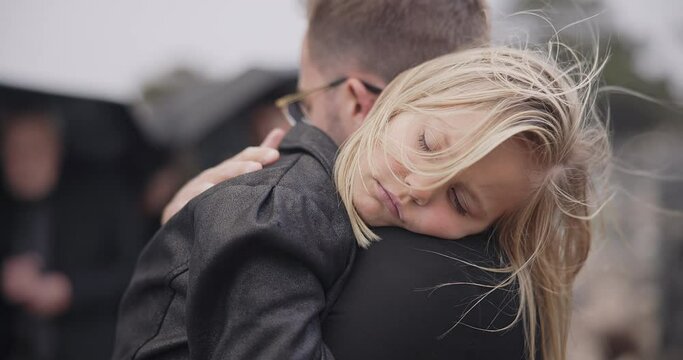 Sad, death and a daughter with her father at a funeral for grief or mourning loss together outdoor. Family, empathy and a man holding his girl child at a memorial service or ceremony for condolences