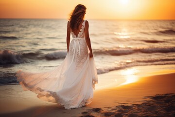 Beautiful woman in white dress walking on the beach at sunset